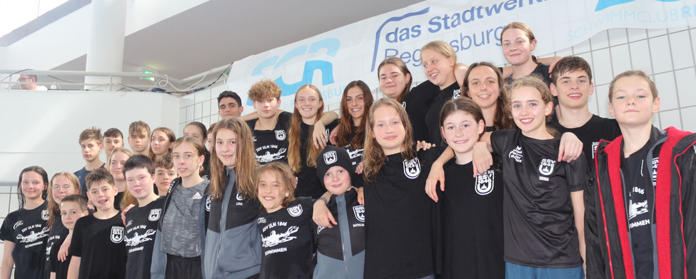Jugendliches Schwimmteam in Vereinskleidung vor Banner Stadtwerk Regensburg