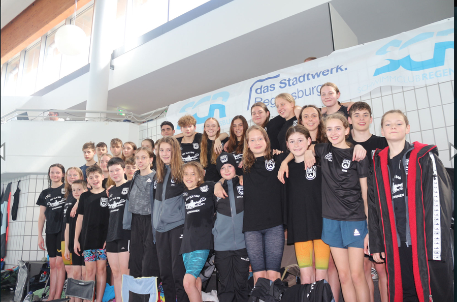 Jugendliches Schwimmteam in Vereinskleidung vor Banner Stadtwerk Regensburg