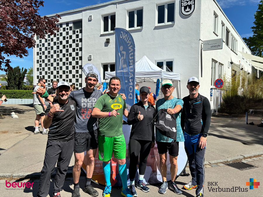 Sechs Läufer und Coaches vor DONAURUNNING Zelt mit Sponsorenlogos