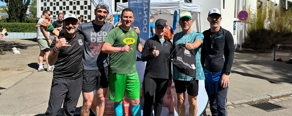 Sechs Läufer und Coaches vor DONAURUNNING Zelt mit Sponsorenlogos