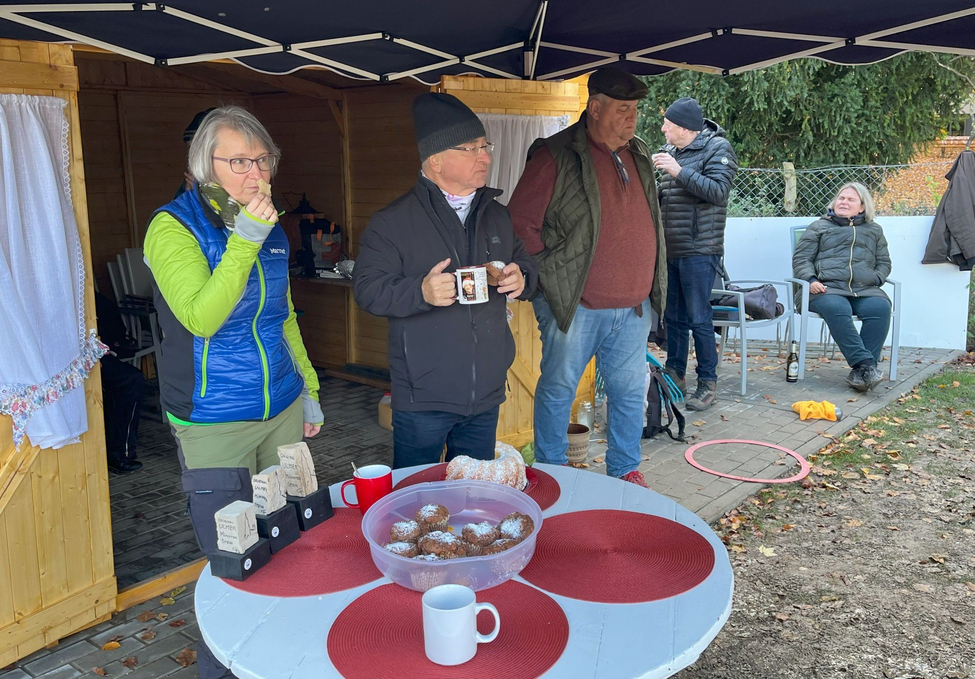 Menschen unter Pavillon neben Tisch mit Muffins und Tassen