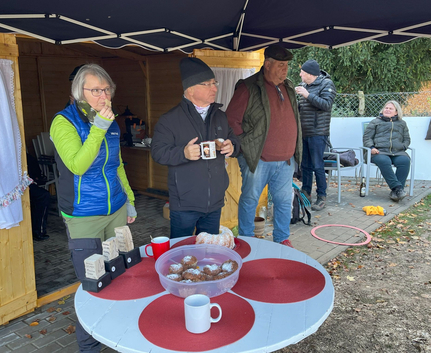 Menschen unter Pavillon neben Tisch mit Muffins und Tassen