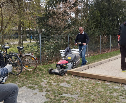 Teilnehmer schiebt Rasenmäher neben Bouleanlage beim 1. Putzete 2025