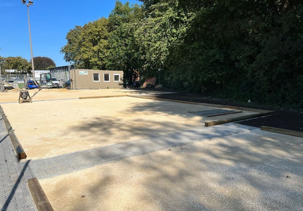 Unfinished gravel courts with wooden borders and construction container