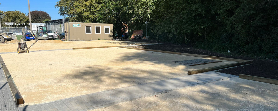 Unfinished gravel courts with wooden borders and construction container