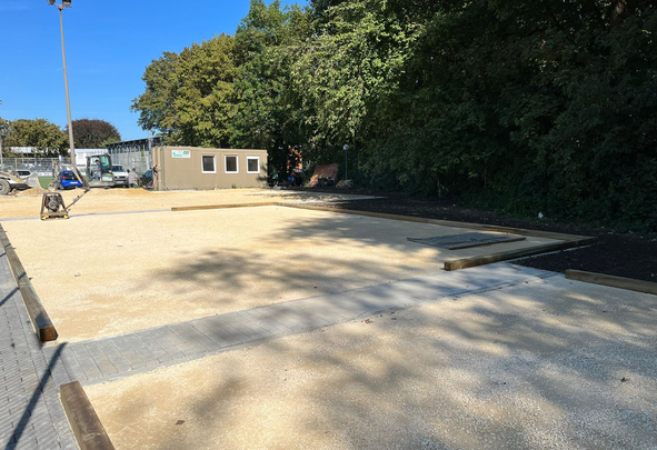Unfinished gravel courts with wooden borders and construction container