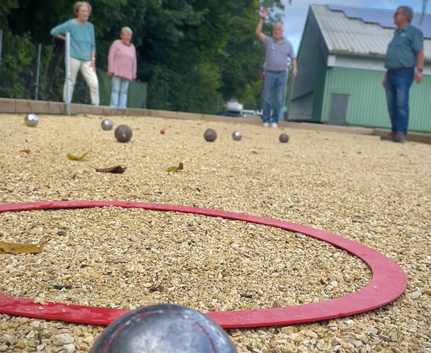 Boule-Kugeln, roter Abwurfring und Teilnehmende auf Boulebahn