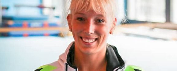 Janine Berger lächelnd in Trainingsjacke in Turnhalle