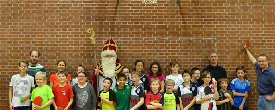 Nikolaus mit Bischofsstab zwischen Kindern mit Tischtennisschlägern in Turnhalle