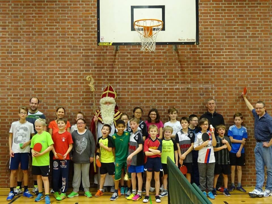 Nikolaus mit Bischofsstab zwischen Kindern mit Tischtennisschlägern in Turnhalle