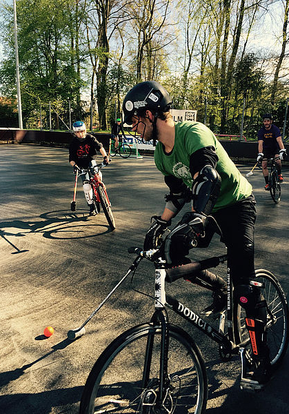 Mehrere Fahrradspieler in Schutzhelmen mit Schlägern und Ball