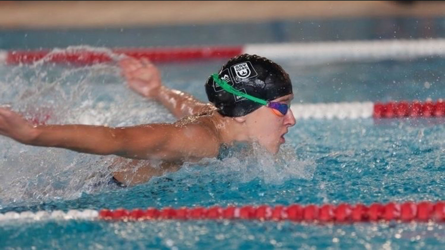 Schwimmer mit schwarzer Badekappe und Schwimmbrille beim Schmetterlingsschwimmen im Wettkampfbecken