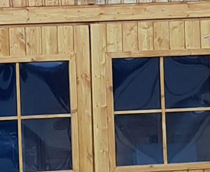 Holzschuppen mit Doppeltür, Sprossenfenstern und Schild Fanny