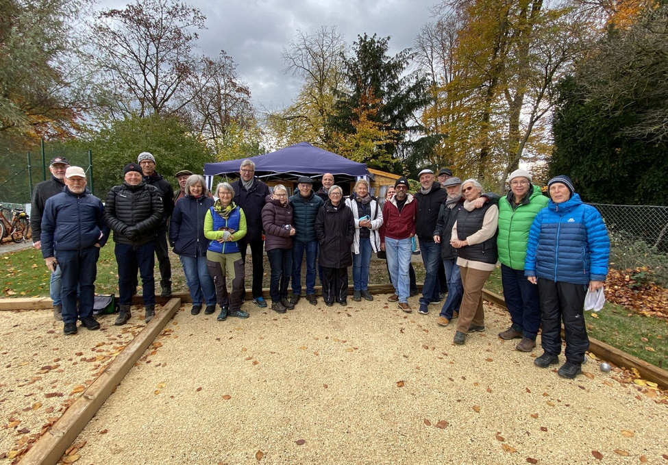 Gruppe Erwachsener auf Bouleplatz vor Pavillon im Herbst