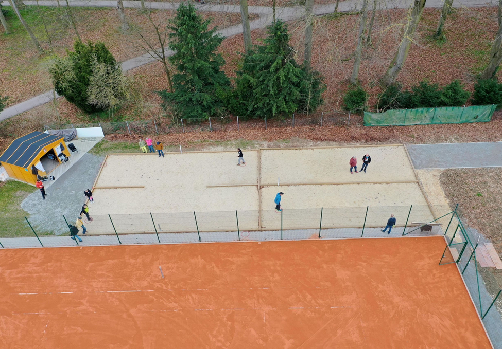 Aerial view of people playing ball game on sand courts