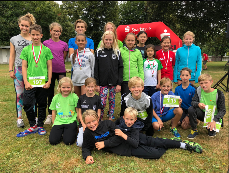 Junge Triathleten in einer Gruppe mit Medaillen und Startnummern