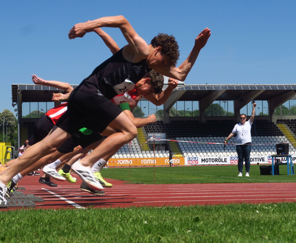 Sprinter starten aus Startblöcken auf Tartanbahn, Starter hebt Pistole