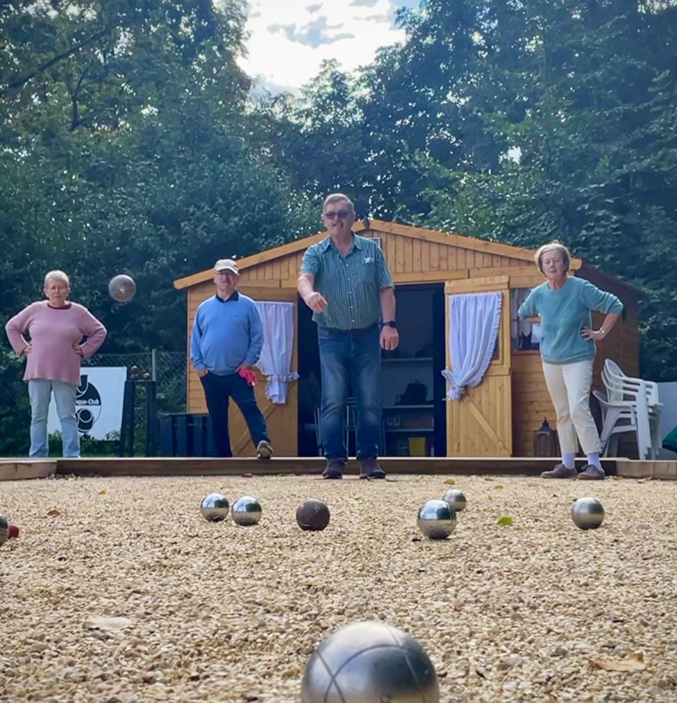 Boule-Kugel und rote Zielkugel auf Kiesbahn mit Spielern im Hintergrund