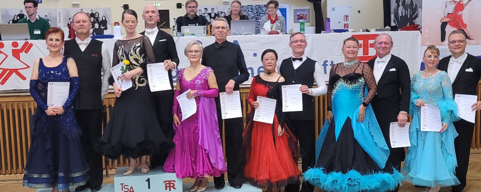 Tanzpaare in Ballkleidung auf Siegerpodest beim Turnier