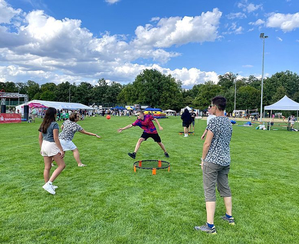 Four people playing round net ball game on grass