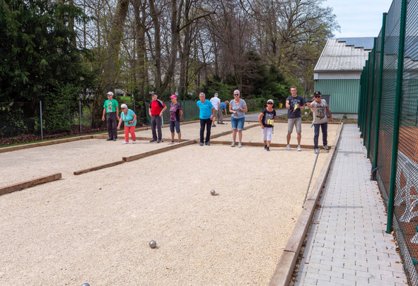 Gruppe Erwachsener spielt Boule auf mehreren Kiesbahnen