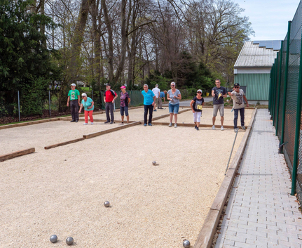 Gruppe Erwachsener spielt Boule auf mehreren Kiesbahnen