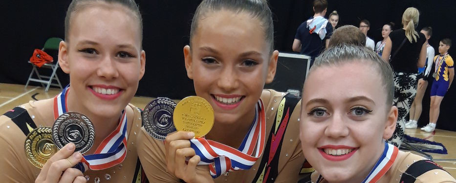 Fünf Turnerinnen in Wettkampfanzügen zeigen Gold und Silbermedaillen
