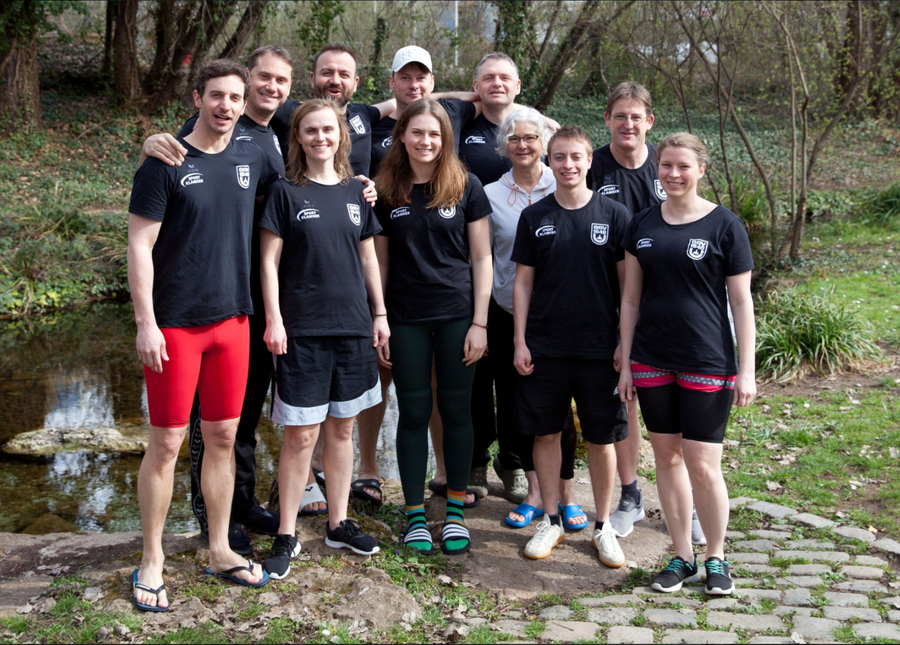 Team von Masters-Schwimmern in Vereinstrikots am Bachufer