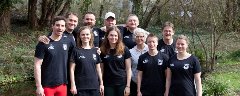 Team von Masters-Schwimmern in Vereinstrikots am Bachufer