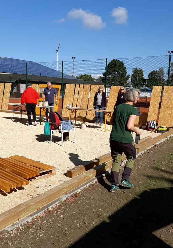 Menschen bauen Holzpaneele an einem umzäunten Außenbereich