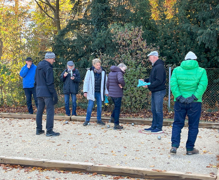 Gruppe von sieben Personen spielt Boule auf Kiesbahn im Herbst