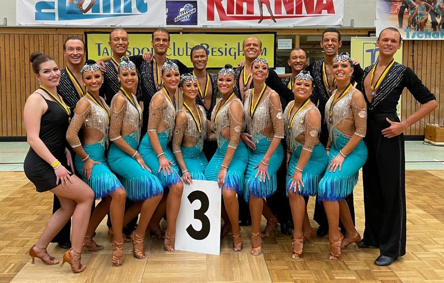 B-Formation Tanzteam in türkisblauen Kostümen mit Schild 3