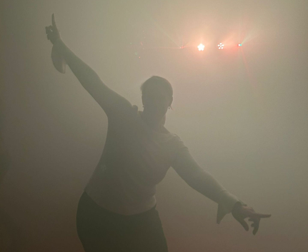 Tanzende Person in dichtem Nebel vor grellen Bühnenlichtern