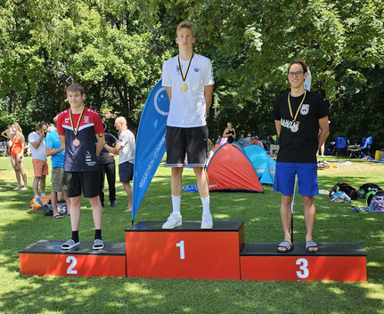 Drei Schwimmer auf Siegerehrungspodest mit Medaillen im Freien