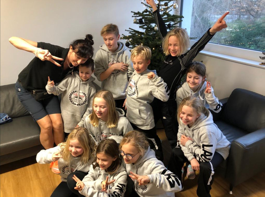 Junge Schwimmerinnen und Schwimmer mit Trainerin vor Weihnachtsbaum