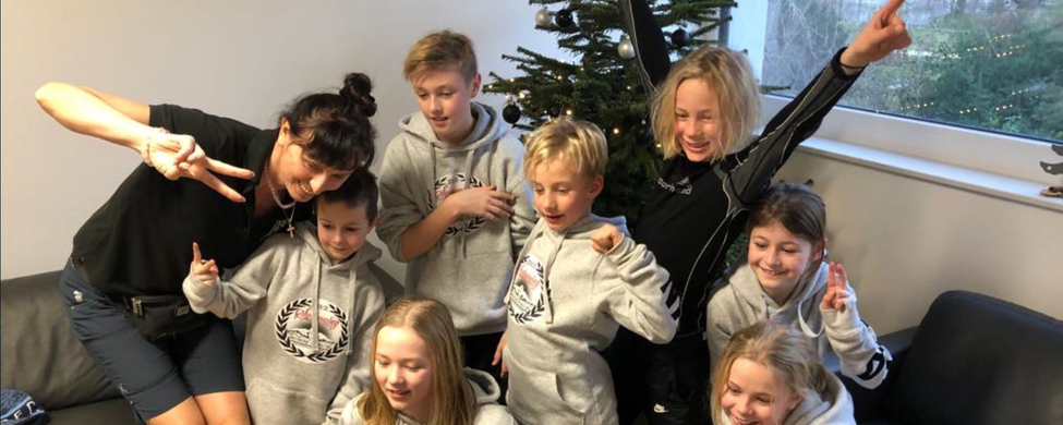 Junge Schwimmerinnen und Schwimmer mit Trainerin vor Weihnachtsbaum