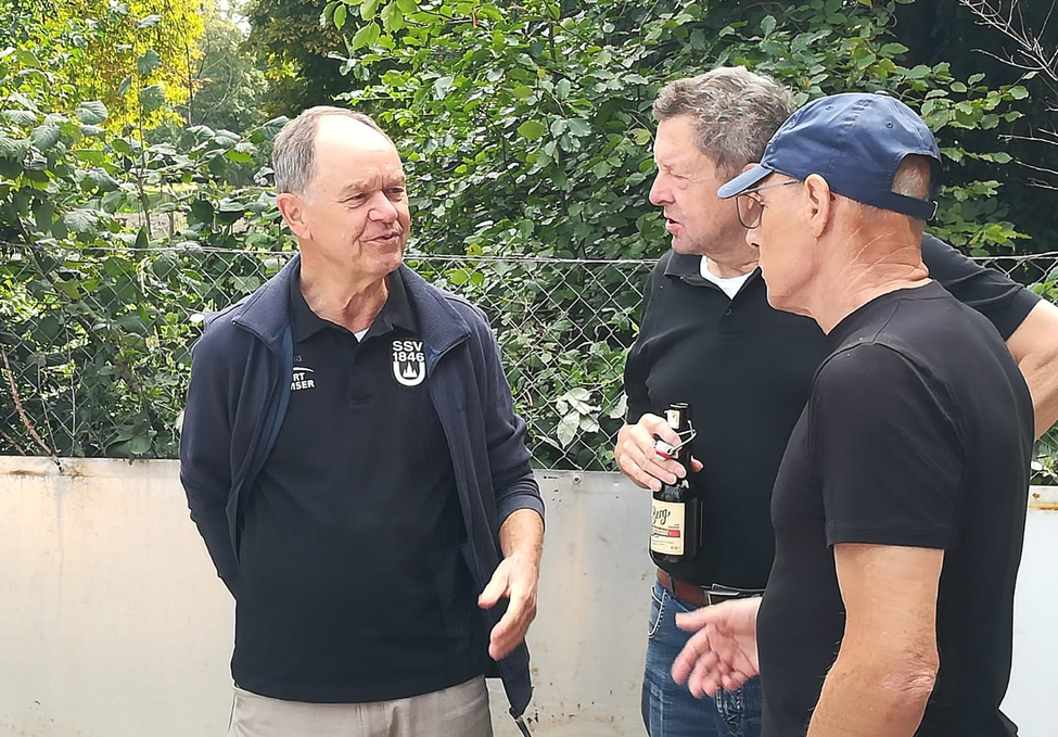 Drei Männer im Freien im Gespräch einer hält Flasche SSV 1846