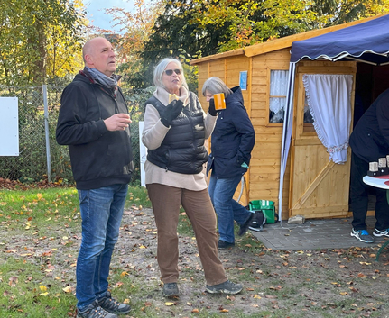 Drei Personen vor Holzhütte im Herbst Frau mit Tasse