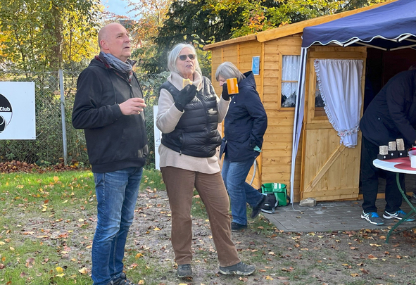 Drei Personen vor Holzhütte im Herbst Frau mit Tasse