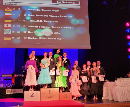 Turnierpodest mit Tanzpaaren, Leinwand zeigt Bernhard Müller / Martina Müller