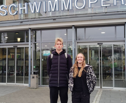 Zwei junge Sportler vor Eingang SCHWIMMOPER