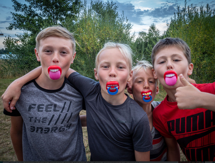 Vier Jungen mit bunten Spielschnullern, T-Shirt-Text Feel the Energy