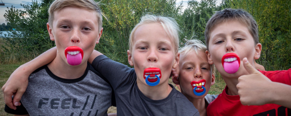 Vier Jungen mit bunten Spielschnullern, T-Shirt-Text Feel the Energy