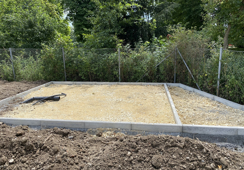 Ausgeebneter Schotterunterbau mit Betonrand und flexiblen Drainagerohren