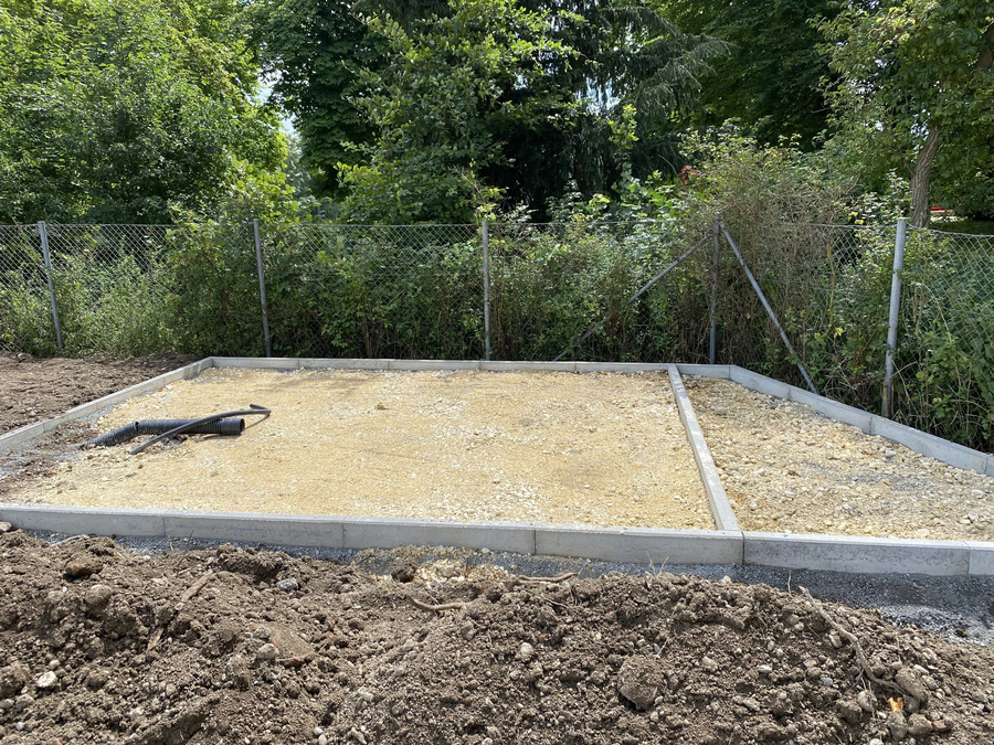 Ausgeebneter Schotterunterbau mit Betonrand und flexiblen Drainagerohren