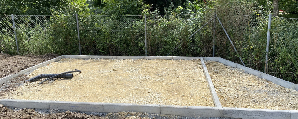 Ausgeebneter Schotterunterbau mit Betonrand und flexiblen Drainagerohren