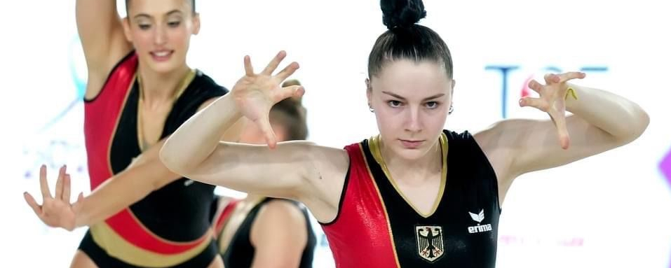 Vordere Aerobic-Turnerin fokussiert, Team in schwarz rot gold, @simoneferraroph European Gymnastics
