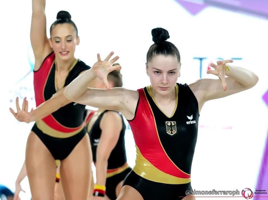 Vordere Aerobic-Turnerin fokussiert, Team in schwarz rot gold, @simoneferraroph European Gymnastics