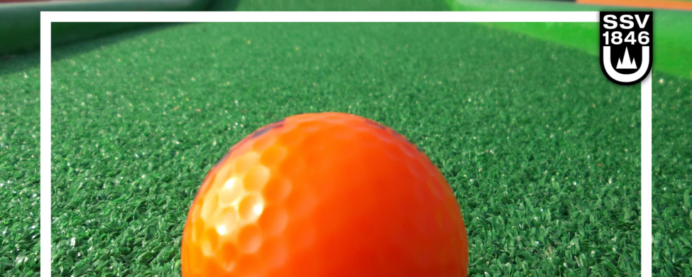 Orange Minigolfball auf grünem Kunstrasen mit Vereinslogo