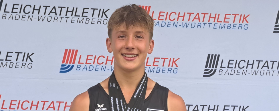 Jugendlicher Athlet mit mehreren Medaillen vor Leichtathletik Baden-Württemberg Banner